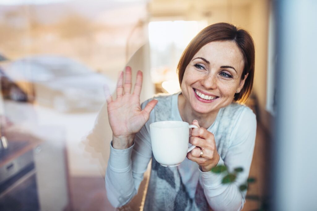 a young woman with cup of coffee looking out of a window
