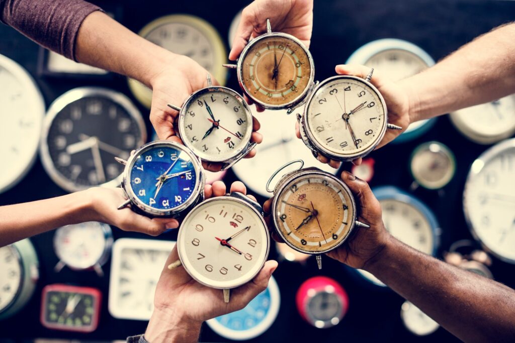 multiple peoples hands holding clocks